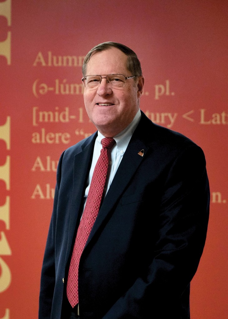 Alumni Association President Kirk Richter poses in front of the mural in the UMSL Office of Alumni Engagement, which displays the definitions of "alumni," "alumna" and "alumnus." (Photo by August Jennewein)
