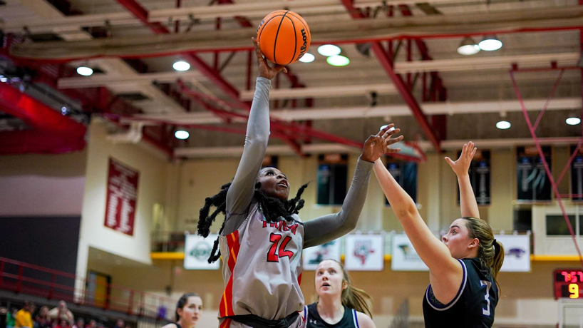 Women's basketball player Kiara Stewart shoots over two defenders