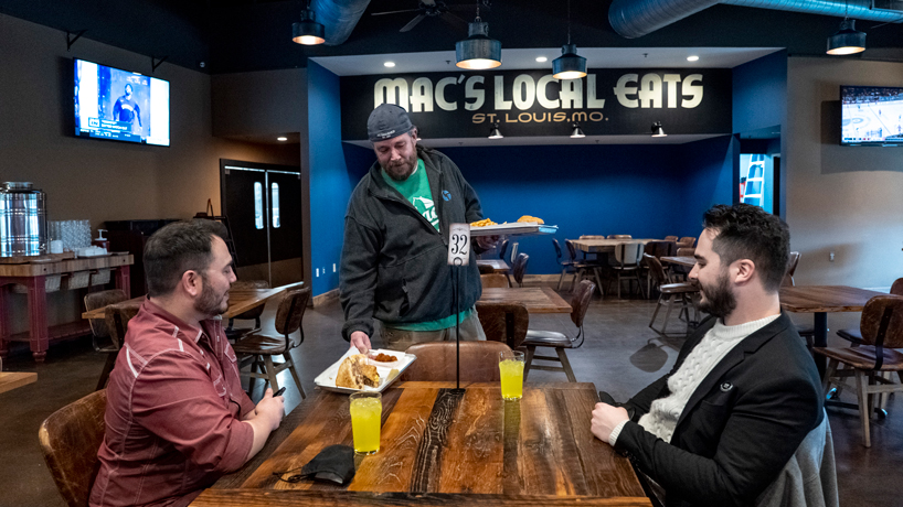 UMSL alumnus Chris "Mac" McKenzie serves lunch to two patrons at Mac's Local Eats