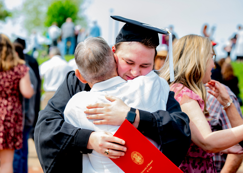 A student hugs his father after commencement