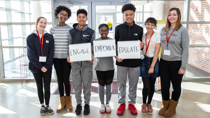 Bridge Program Saturday Academy Students holding signs that say Engage, Empower, Educate