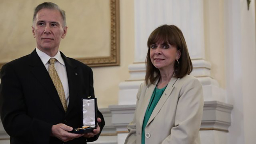Greek President Katerina Sakellaropoulou presents Michael Cosmopoulos with the Golden Cross of the Order of the Phoenix