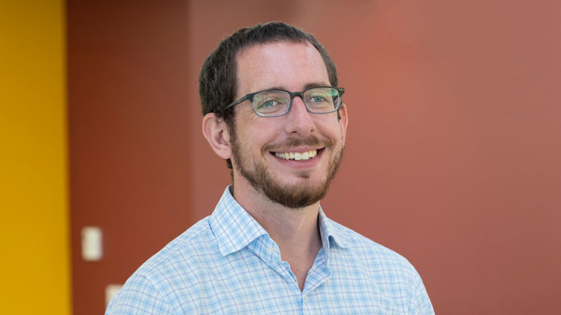 Man looks into camera, smiling.