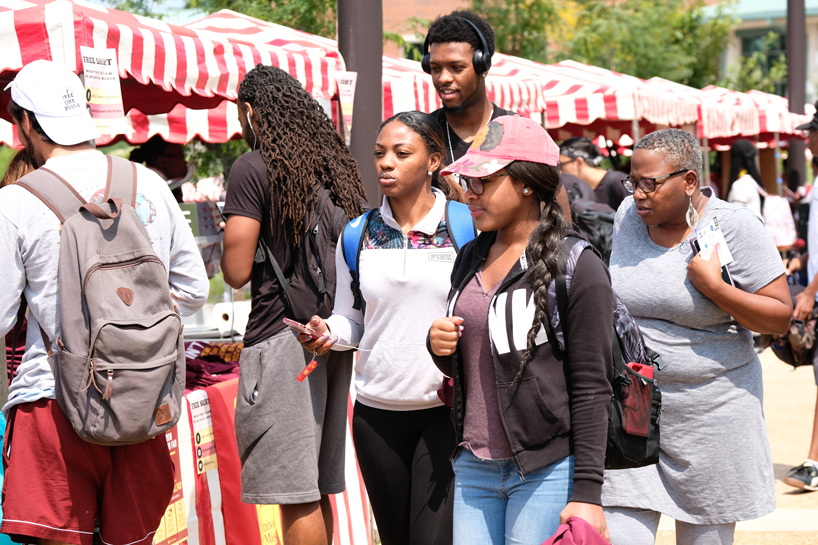 Students walk past booths at a Fall semester involvement event
