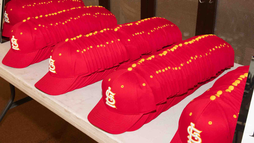 Hundreds of UMSL-themed St. Louis Cardinals hats sit on a table