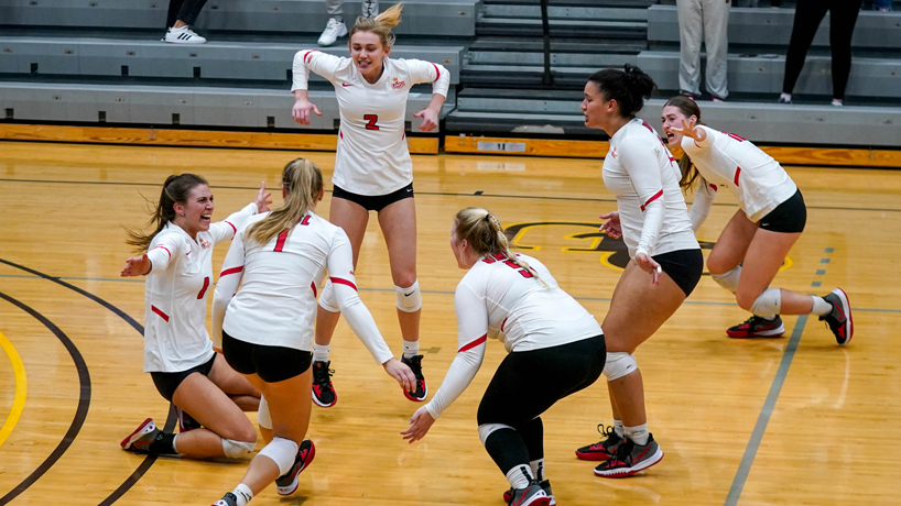 Charlotte Richards slides on her knees amid her teammates after the UMSL volleyball team clinched the Midwest Regional title