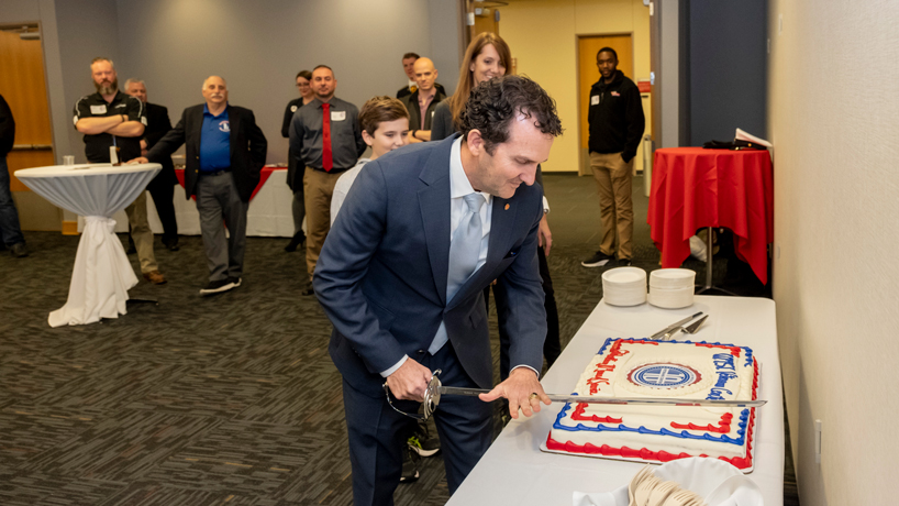 Jim Craig cuts a cake with a sword at the Veterans Center's 10th anniversary celebration