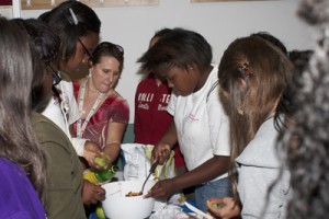 Pam Ingram, nutrition program associate with the University of Missouri Extension Service (center, in red), directs a group of campers at the UMSL Girls’ Leadership Camp as they prepare a fruit salsa as part of a healthy eating class.