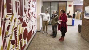 Visitors to the Lucas Hall foyer examine UMSL student Charlie Nowell's finished mural.
