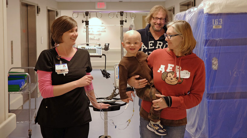 Jori Derner (left), a nurse at St. Louis Children's Hospital, holds Viktor Ebers' IV as he and his parents take a stroll. Derner graduated from the RN to BSN online program in 2013 and is now in the graduate nursing program at UMSL. (Photo by August Jennewein)