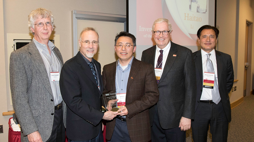 Haitao Li (center),  an associate professor logistics and operations management at UMSL, was named Inventor of the Year by the National Academy of Inventors. The recognition was announced during the annual Research & Innovation Week April 17-24 at UMSL. Pictured (from left) are Professor Logistics and Operations James Campbell, Chancellor Tom George, Li, College of Business Administration Dean Charles Hoffman and Vice Provost of Research Nasser Arshadi. (Photo by August Jennewein)