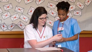 Nursing graduate Christy Yates plays patient as Little Nursing School student Gena Hill practices taking a pulse. (Photo by August Jennewein)