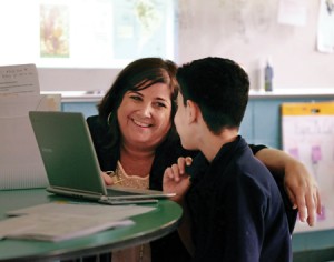 Julie Frugo, head of school at Premier Charter School, talks with a student about his class assignment.