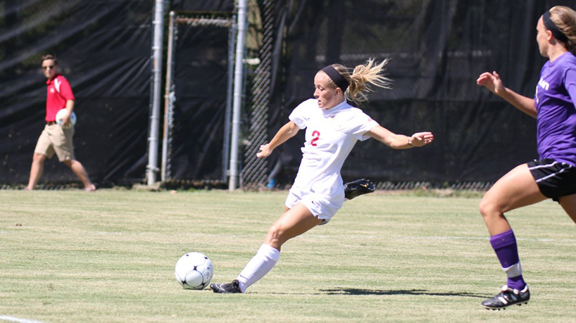 Soccer player Miriam Taylor is kicking a soccer ball against Lewis.