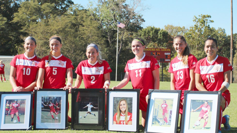 UMSL women's soccer seniors Kayla Delgado (10), Taylor Tosovsky (5), Miriam Taylor (2), Miranda Buettner (11) Amber Daly (23) and Kirsten Crabtree (16) pose together with framed photos of each of them.