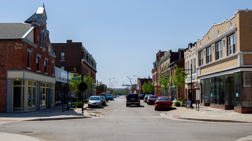 An SUV drives down the street through the Old North Neighborhood toward the Arch