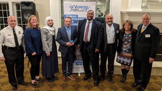 Anthony Harper holds a Blue Heart Award while surrounded by members of the Gateway Human Trafficking board