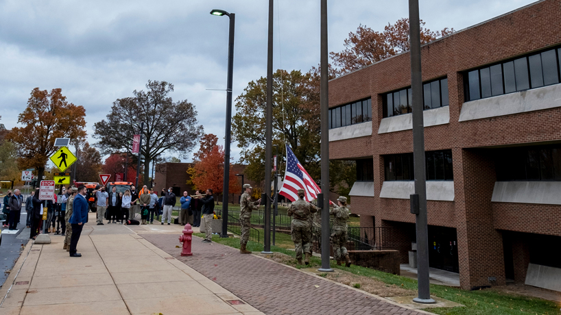 Members of UMSL Army ROTC raise the American flag outside Woods Hall as Krishaun Dotson-Orange plays his trumpet