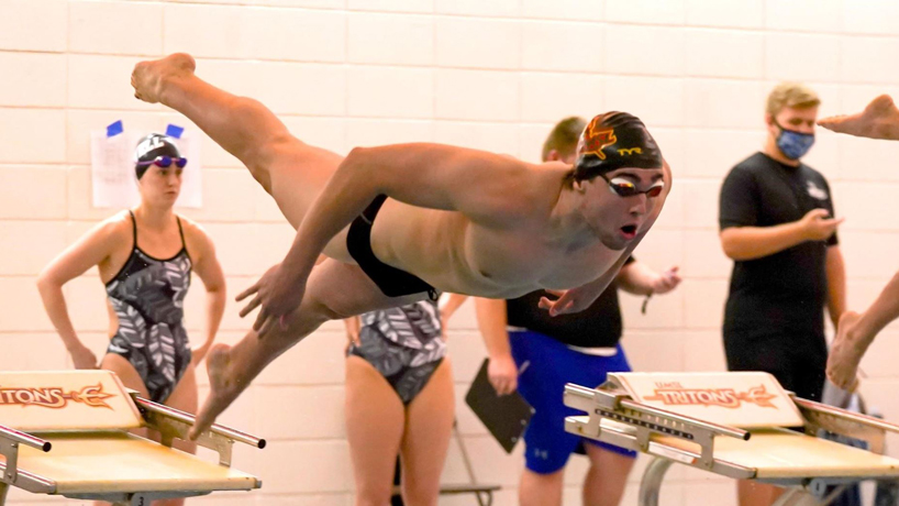 Swimmer Jon Osa dives into the poll during a race