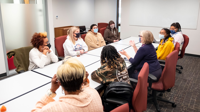 Students and faculty members sit around the table in the School of Social Work's new conference room