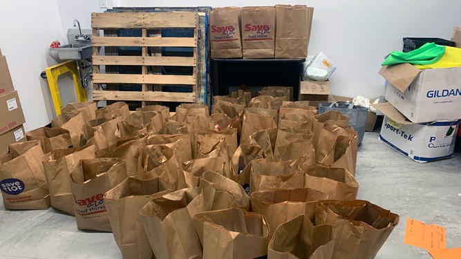 Paper bags filled with food, purchased and donated by student-athletes, lie on the floor of the Triton Pantry