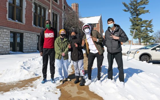 Students Sadaht Sanda, Aria Spencer, Jay King, Tyler Haynes and Zufarbek Zaynutdinov flash peace signs while walking on snowy South Campus