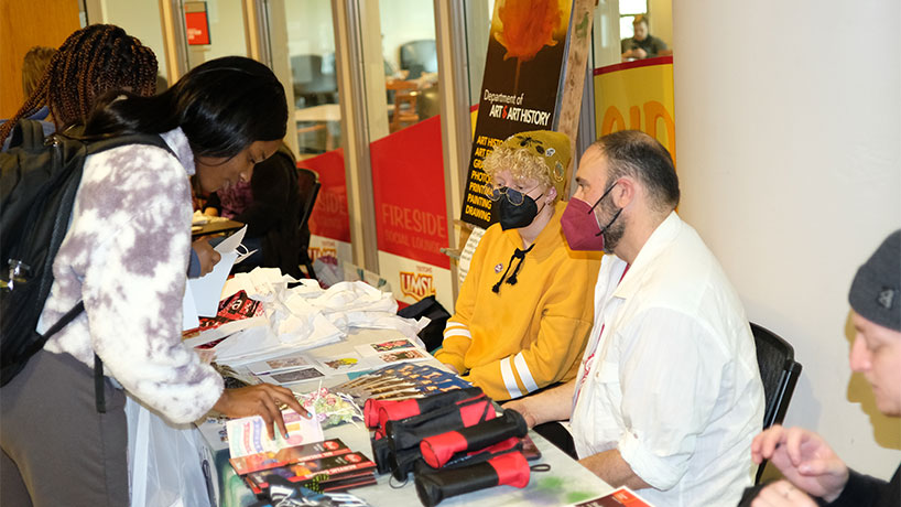 Two students visit the table of the Artists Anonymous Student organization at the UMSL Spring Student Involvement Expo