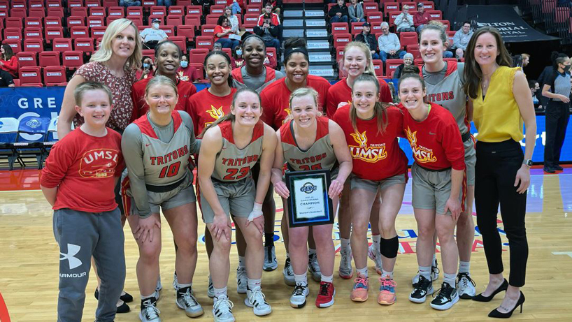 The UMSL women's basketball team gathers with a plaque commemorating their first-place finish in the GLVC Central Division