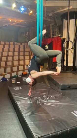 Madeleine Trotier hangs upside down while performing aerial acrobatic pose