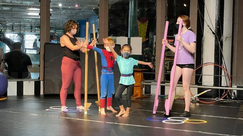 Madeleine Trotier teaches two children to balance on mat