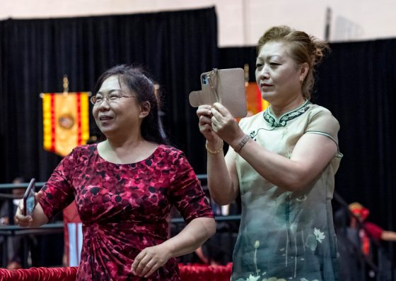 Family members move into position to take photos of their graduates with their camera phones