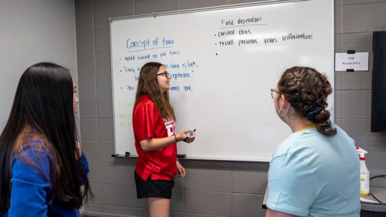 Rachel Jacklin brainstorms with two students at whiteboard