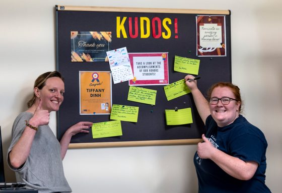 Administrative Associate Ann Marie Klues (at left) and Student Recruitment Specialist Jenna Haddock update the Kudos board last week in the Pierre Laclede Honors College