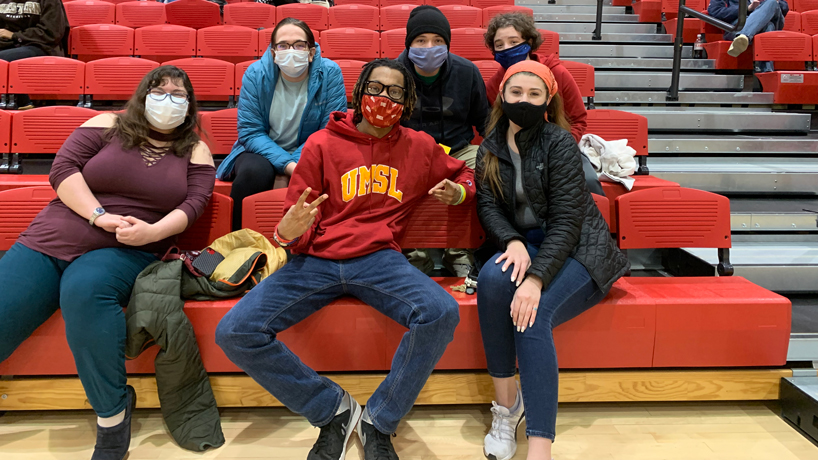 Members of UMSL Social Peers sit in the stands of a Tritons basketball game
