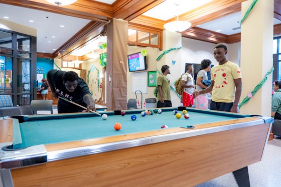 A student lines up a shot on the pool table in Oak Hall as his friend looks on