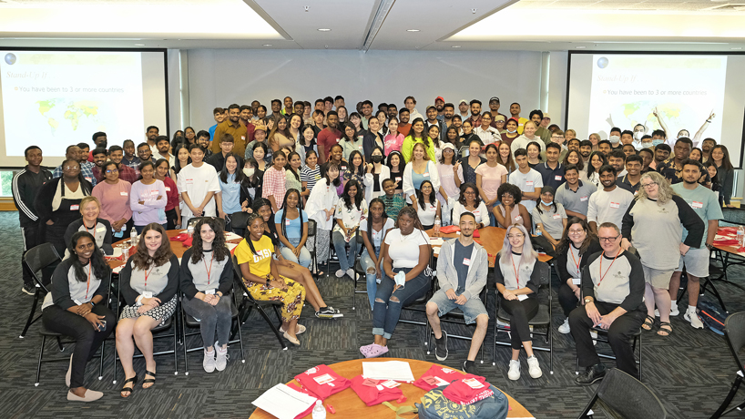 A group of more than 100 international students gathered for a group photograph in the MSC Century Rooms