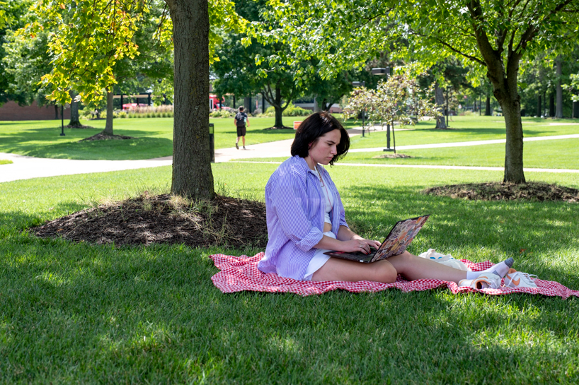 Senior social work major Madalyn Dueker studies in the grass outside the Thomas Jefferson Library