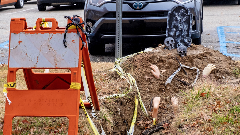 A construction hole is decorated with a scull, bones, a headstone and other Halloween-themed decorations