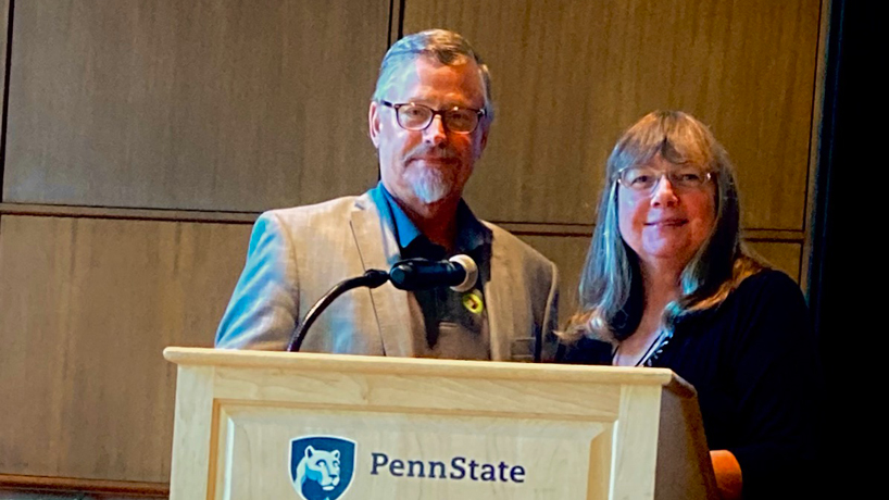 Douglas Swanson and Ann McCauley stand behind a lectern at a conference at Penn State