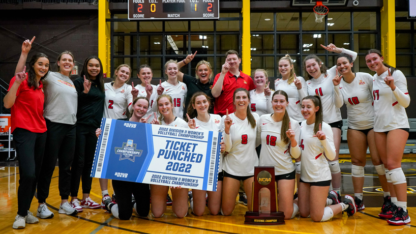 UMSL volleyball players gather together holding up No. 1 fingers and a Tickets Punched sign after winning the NCAA Division II Midwest Regional