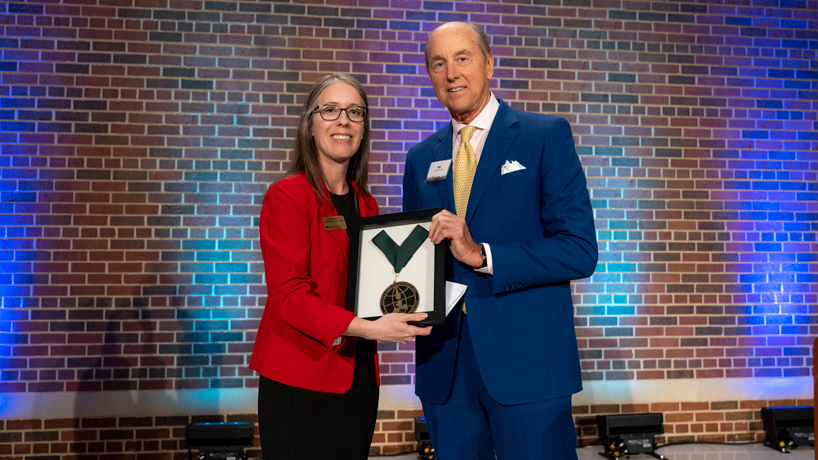 Lisa Capone presents Robert R. Hermann Jr. with a framed World Ecology Award medal commemorating the award being named for his father