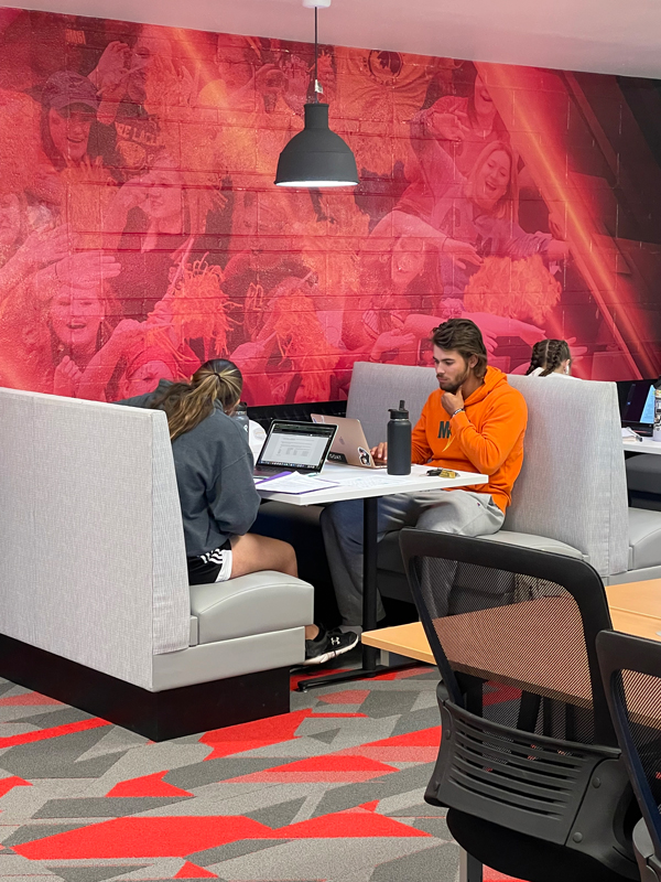 Two student-athletes sit at a booth and study