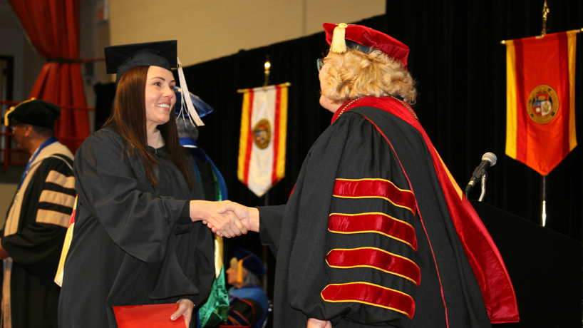 A student shakes hands with Chancellor Kristin Sobolik during commencement