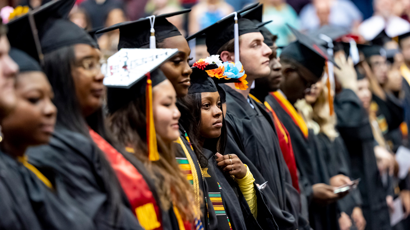 New graduates stand in caps and gowns during a commencement ceremony
