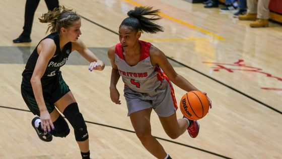 Women's basketball player Jalysa Stokes dribbles past a defender