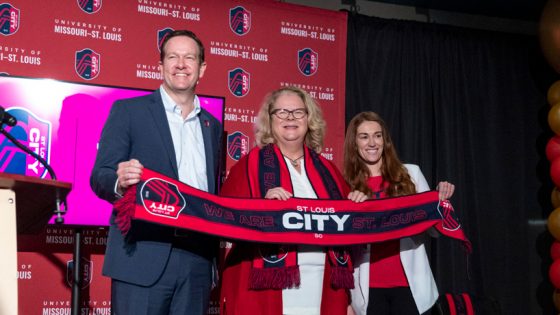 St. Louis CITY SC Chief Revenue Officer Dennis Moore joins UMSL Chancellor Kristin Sobolik and CITY Correspondent Kristin Carver in holding up a scarf after announcing a new partnership between the St. Louis soccer club and the university