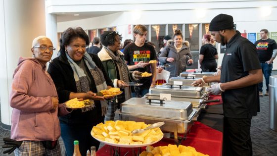 People stand in line being serviced food at the Black History Month Kickoff