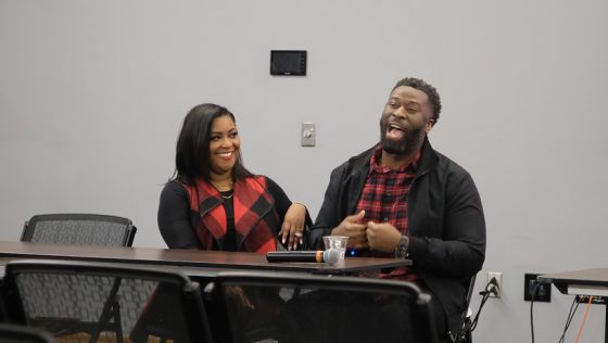 Chavon and Jacob Beard, black woman and black man both dressed in red and black sitting, Jacob answers question while Chavon looks on