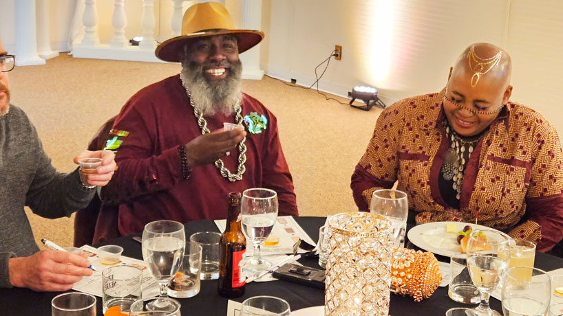 Black couple are smiling and laughing at a table during a dinner event.