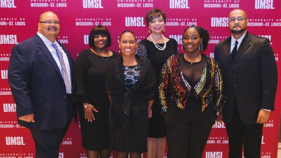 Black Faculty and Staff Association executive committee stands in front of an UMSL backdrop smiling.